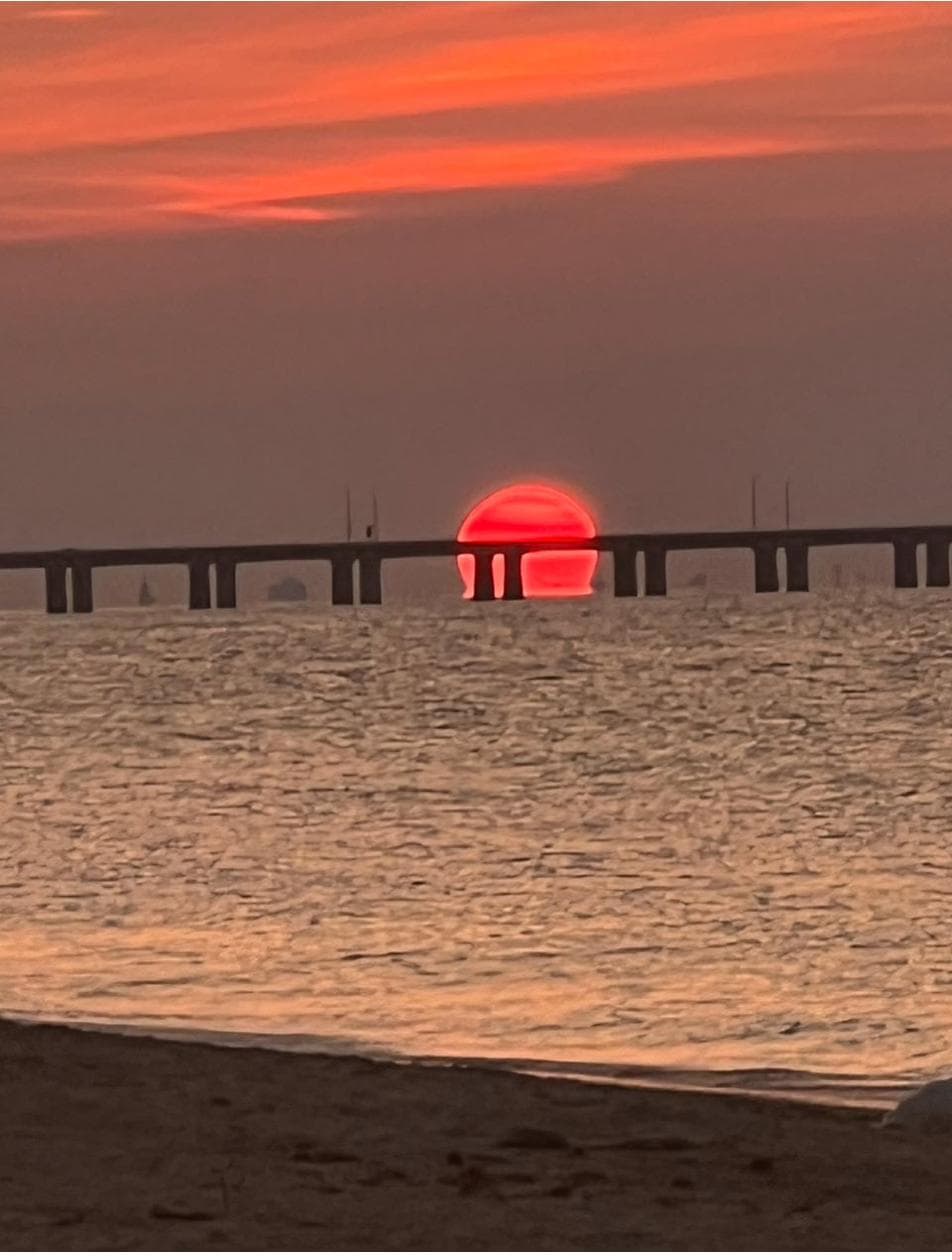 A massive red sun setting behind the Lesner Bridge over Shore Drive